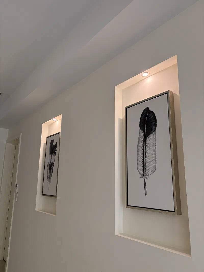 Recessed downlights above framed artwork in a hallway